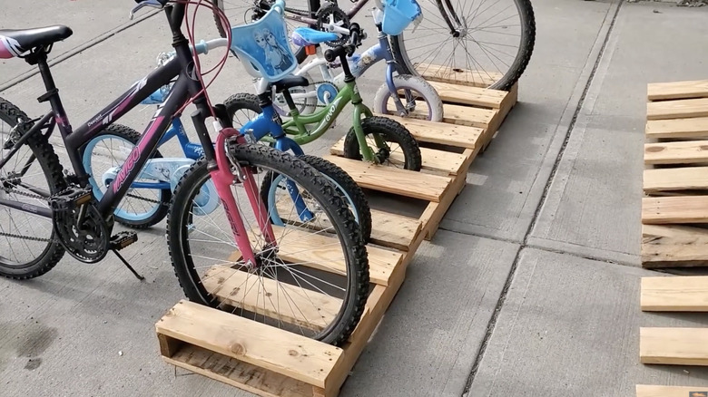 A floor bike rack organizer with five bikes inside it made from a wood pallet.
