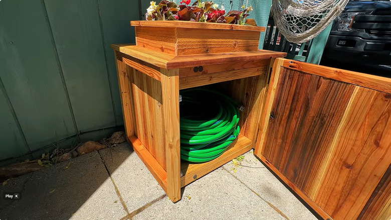 Garden hose hideaway with old wood pallets