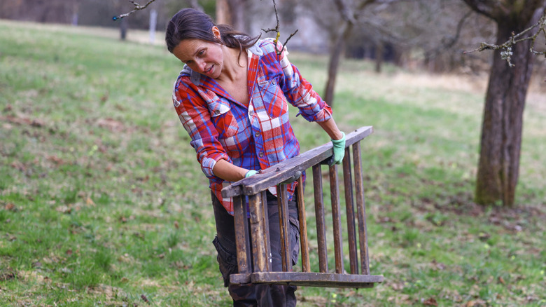 Woman in plaid shirt holding an old wood ladder