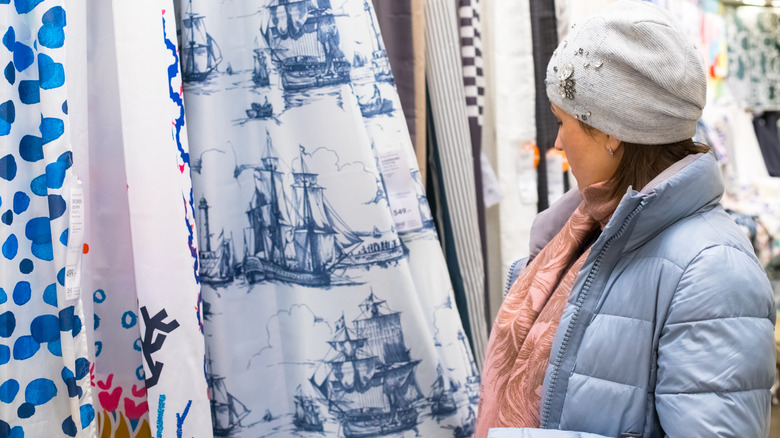 Young woman browsing different shower curtain patterns at store