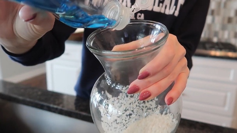 Woman putting dish soap inside a glass vase with rice inside