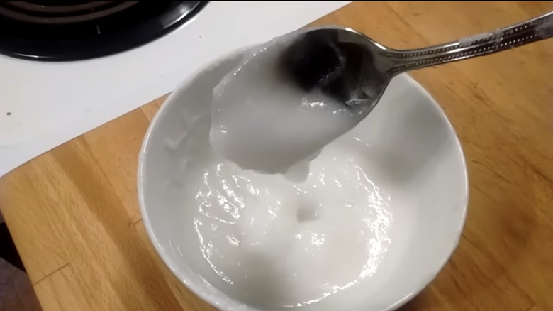 White rice glue in a white bowl with a silver spoon scooping some glue out