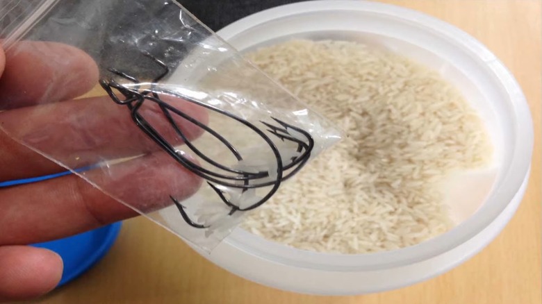 hand holding fishing tackles in nylon above dish with rice inside