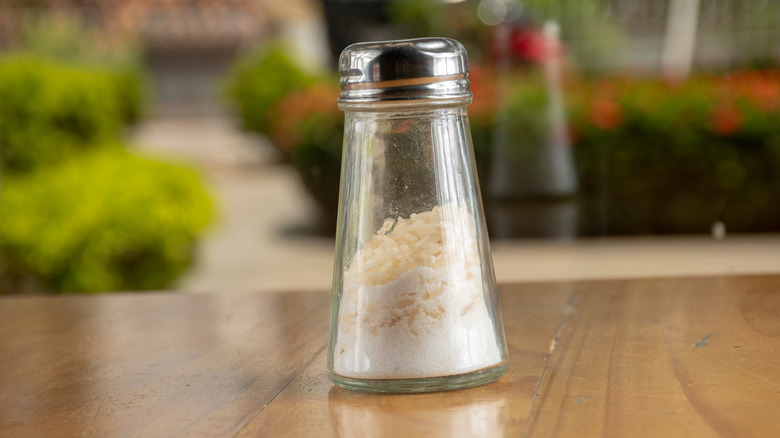 Salt shaker filled with salt and grains of dry rice
