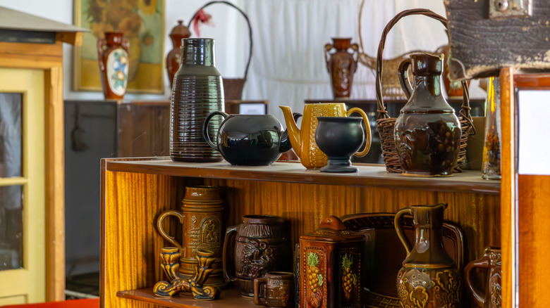 A collection of vintage pottery sits on a wooden shelf