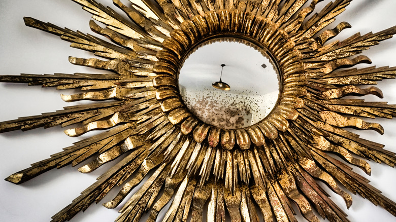 A golden starburst mirror is shown in a detail shot