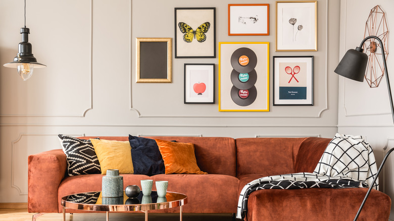 A room full of original artwork and prints on the wall behind a couch