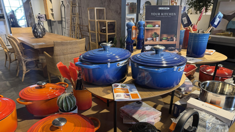 Colorful blue and orange Le Creuset products on display in a store.