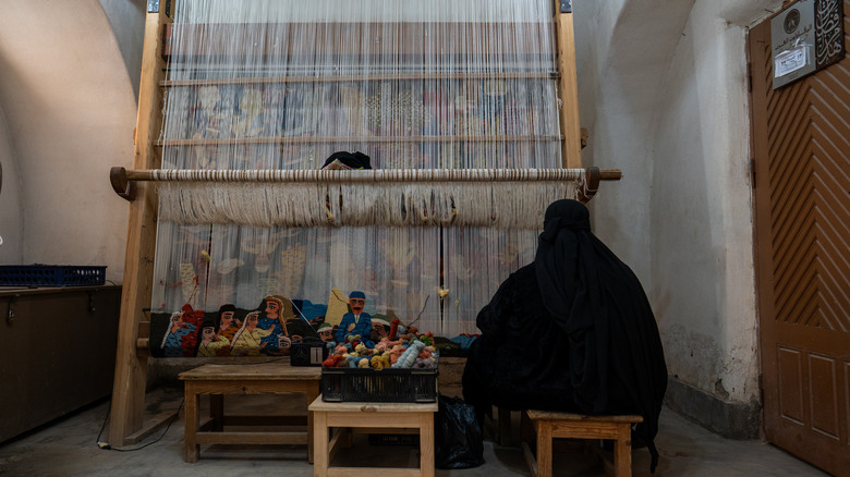Woman weaving rug on a loom