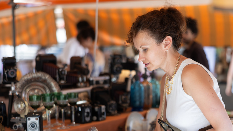 A woman checks out glassware at a vintage market.
