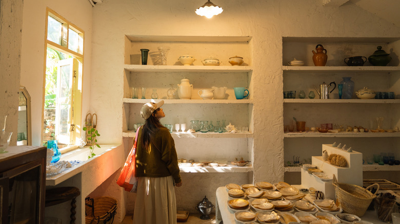 A person shopping for pottery in a thrift store