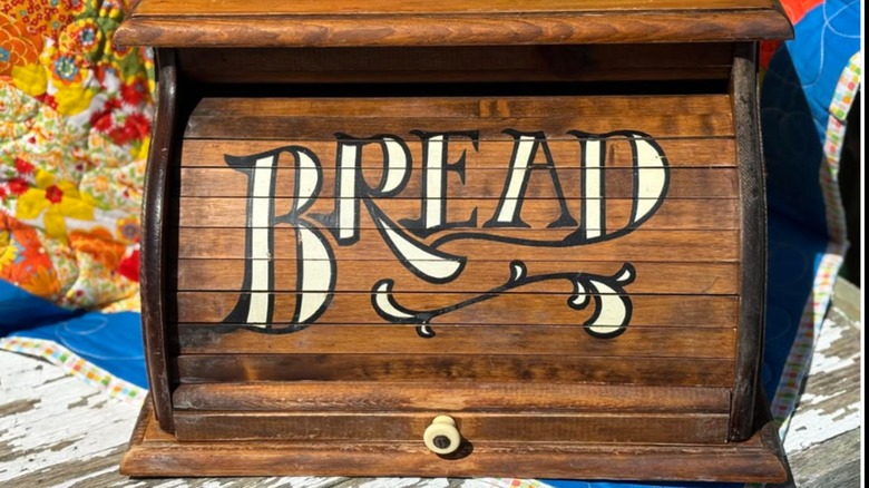 A vintage rolltop bread box with the word "BREAD" printed on it.