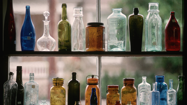 vintage glass in various colors on shelves in front of window