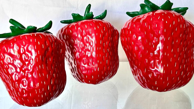 Three brightly colored Strawberry-shaped cookie jars