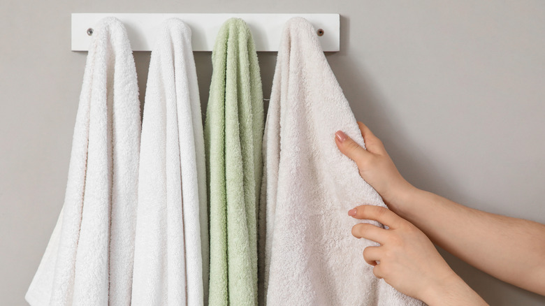Person reaching for bathroom towels hanging on hooks