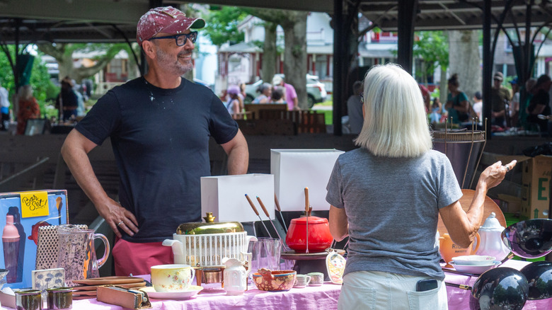 A man sells various vintage bowls and dishes at a vintage market