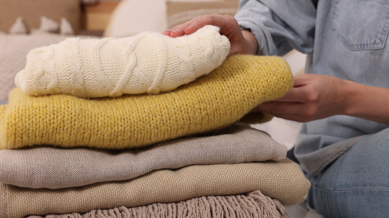 Woman sitting with pile of folded blankets