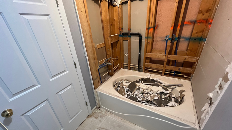 A bathtub filled with debris from demolition of the alcove-style tub.