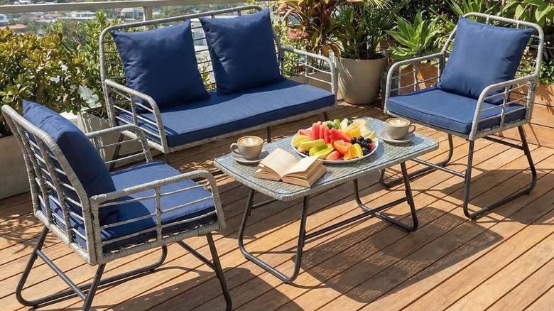 A patio furniture set with blue cushions sits around a coffee table