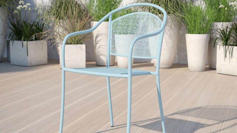 A sky blue metal chair sits on a wooden patio surrounded by potted plants