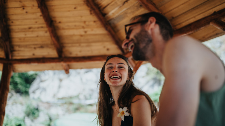Two people smile and laugh under a gazebo