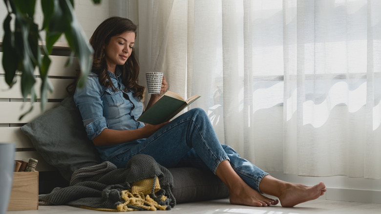 a woman reading a book a cushion in a cozy corner