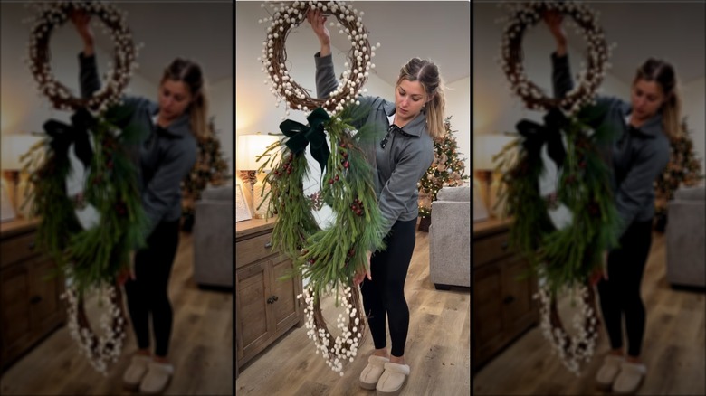 A woman holds up a triple wreath for the holidays.