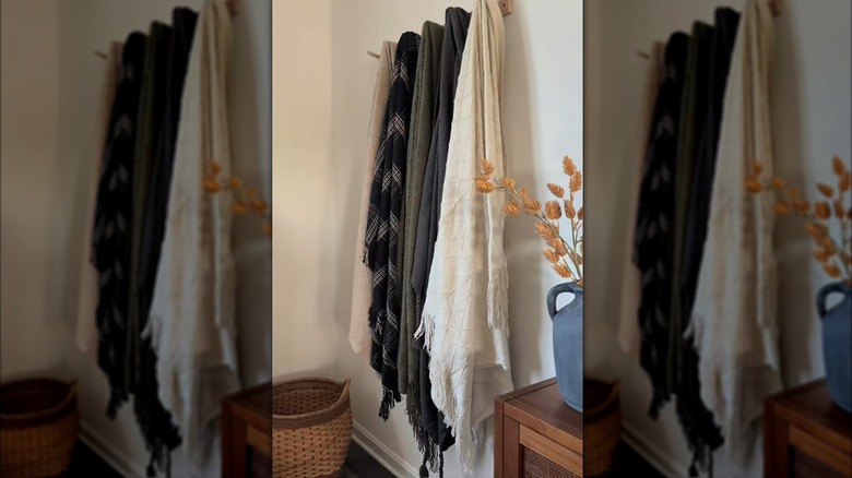 Blankets hung on wooden wall hooks for storage and decorative purposes in traditional living room