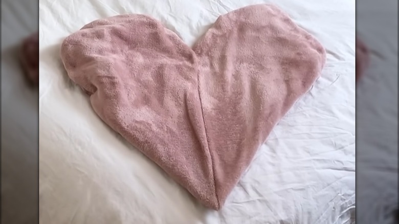 Soft fur blanket curved into heart shape on white bed