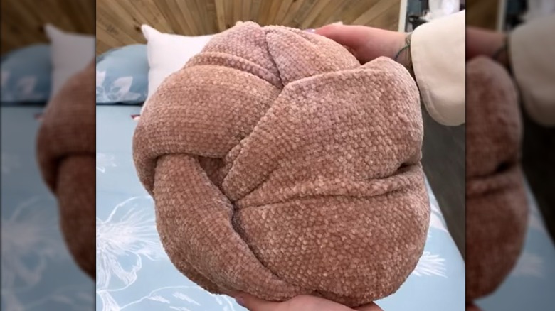 Pink throw blanket rolled into trendy knot-shaped pillow