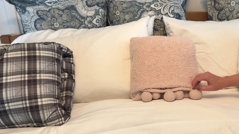 White king bed with assorted throw blankets arranged as throw pillows