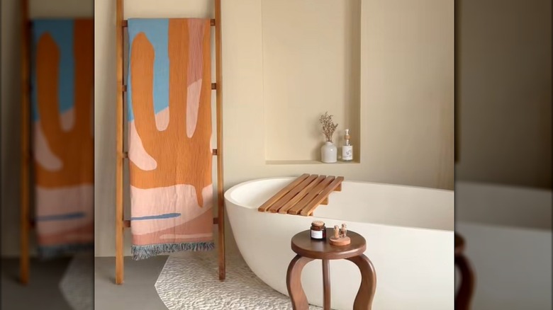 Modern abstract blanket hanging on wood ladder beside bathtub in modern bathroom