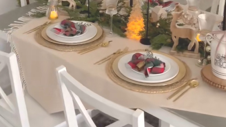 Flat beige throw used as festive tablecloth underneath dinnerware and a Christmas centerpiece