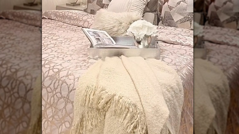Chic bedroom with fringed blanket underneath silver tray and elegant decor