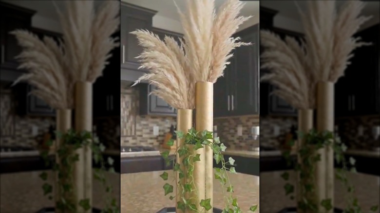 Glamorous DIY vase made of paper towel tubes and artificial foliage on stone kitchen countertop