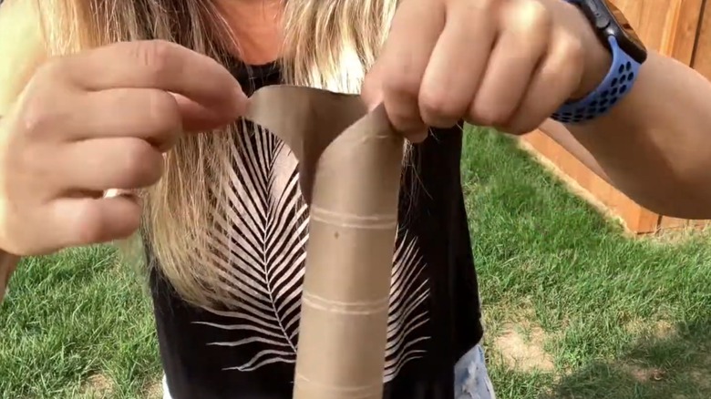Woman tearing up brown paper towel tube for compost