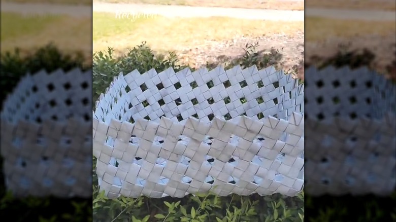 Woven basket made of cardboard paper tubes on grass outside