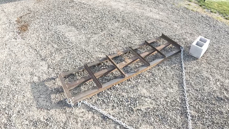 Scrap metal welded together dragging over gravel