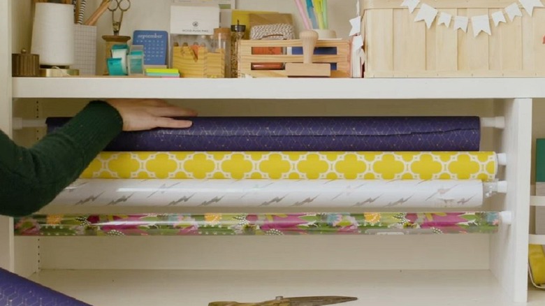 Woman using tension curtain rods to hold wrapping paper