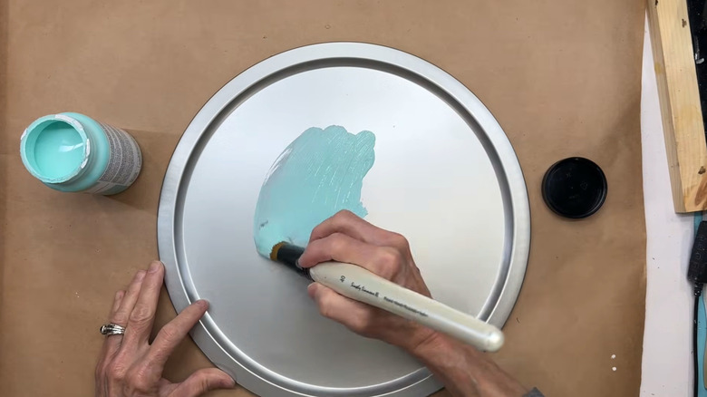 Person painting a Dollar Tree pizza pan blue
