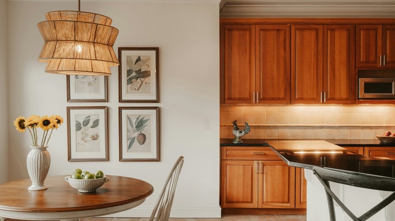 A honey oak kitchen with a small table, white walls, pictures, and white decor