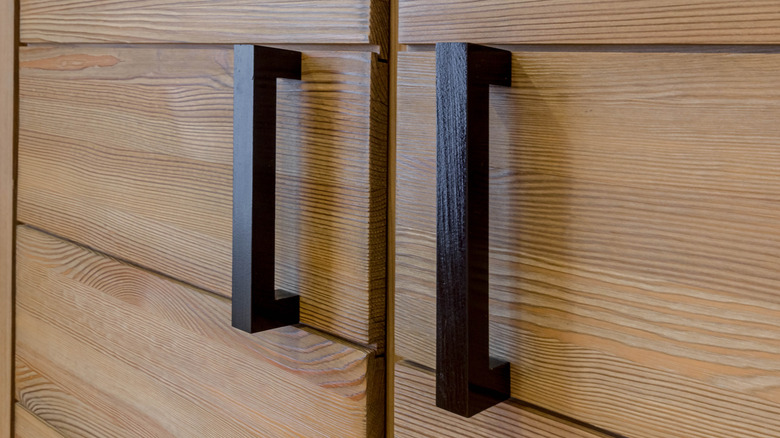 A closeup of wooden cabinets with black matte hardware