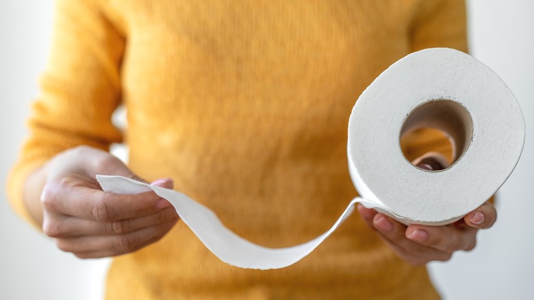 Woman unrolling fresh toilet paper roll