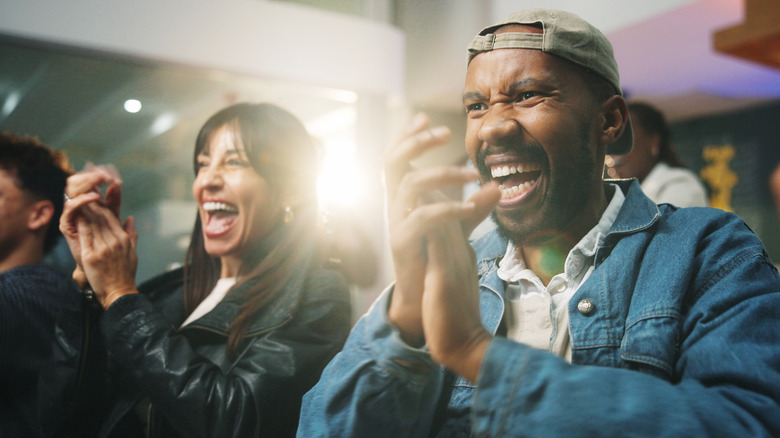 Smiling people cheer on their team at a Final Four house party