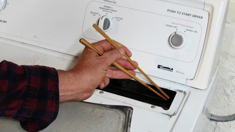 Man using chopsticks to remove dryer lint