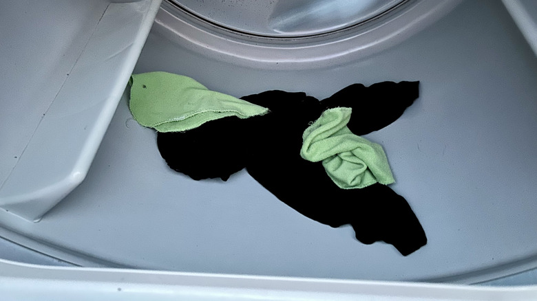 a black shirt and two green washcloths in a dryer