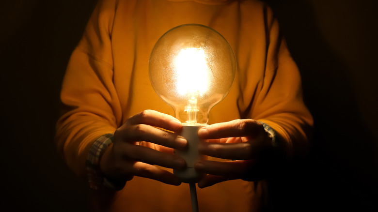 Person holding a light bulb glowing orange