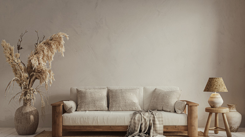 A wall covered in beige limewash paint, with a count, side table, and decor in front of it