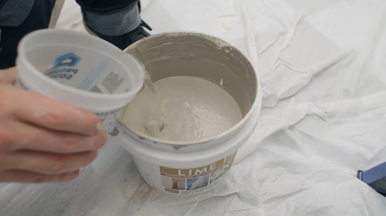 Hand adding water to limewash paint