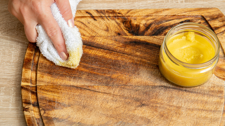 A person applying beeswax to a cutting board with a cloth